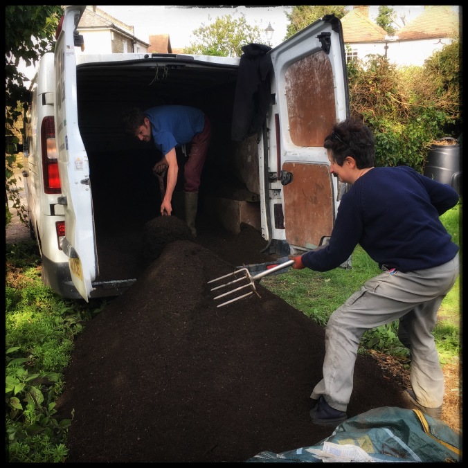 Richard and Elisa shovelling compost out of the back of Richard's van